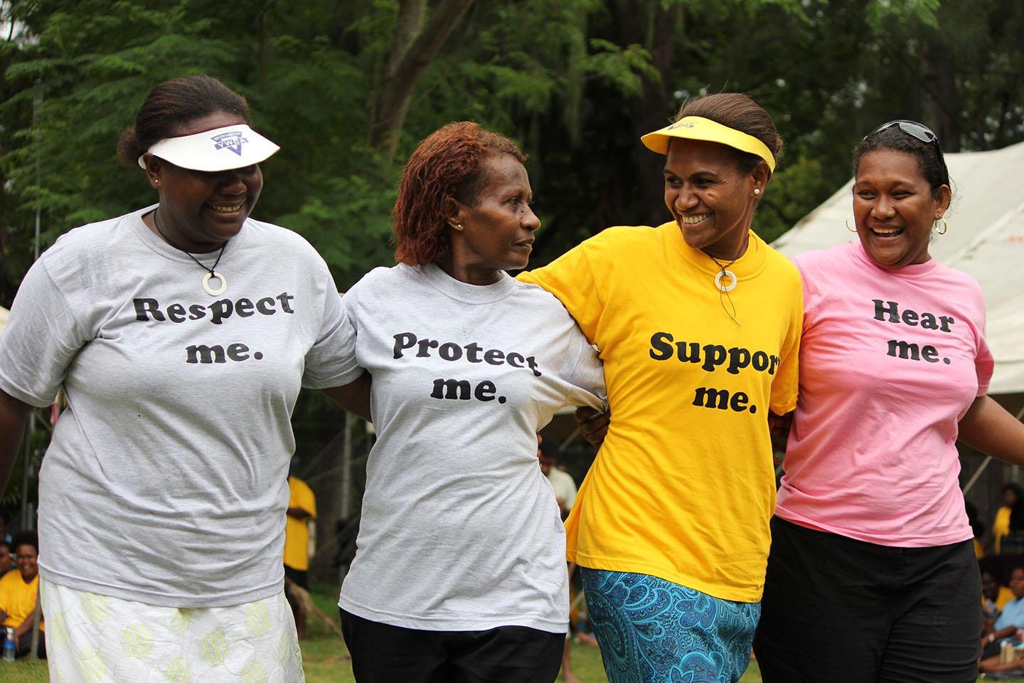 Women at a community event in shirts reading Respect me, Protect me, Support me, Hear me
